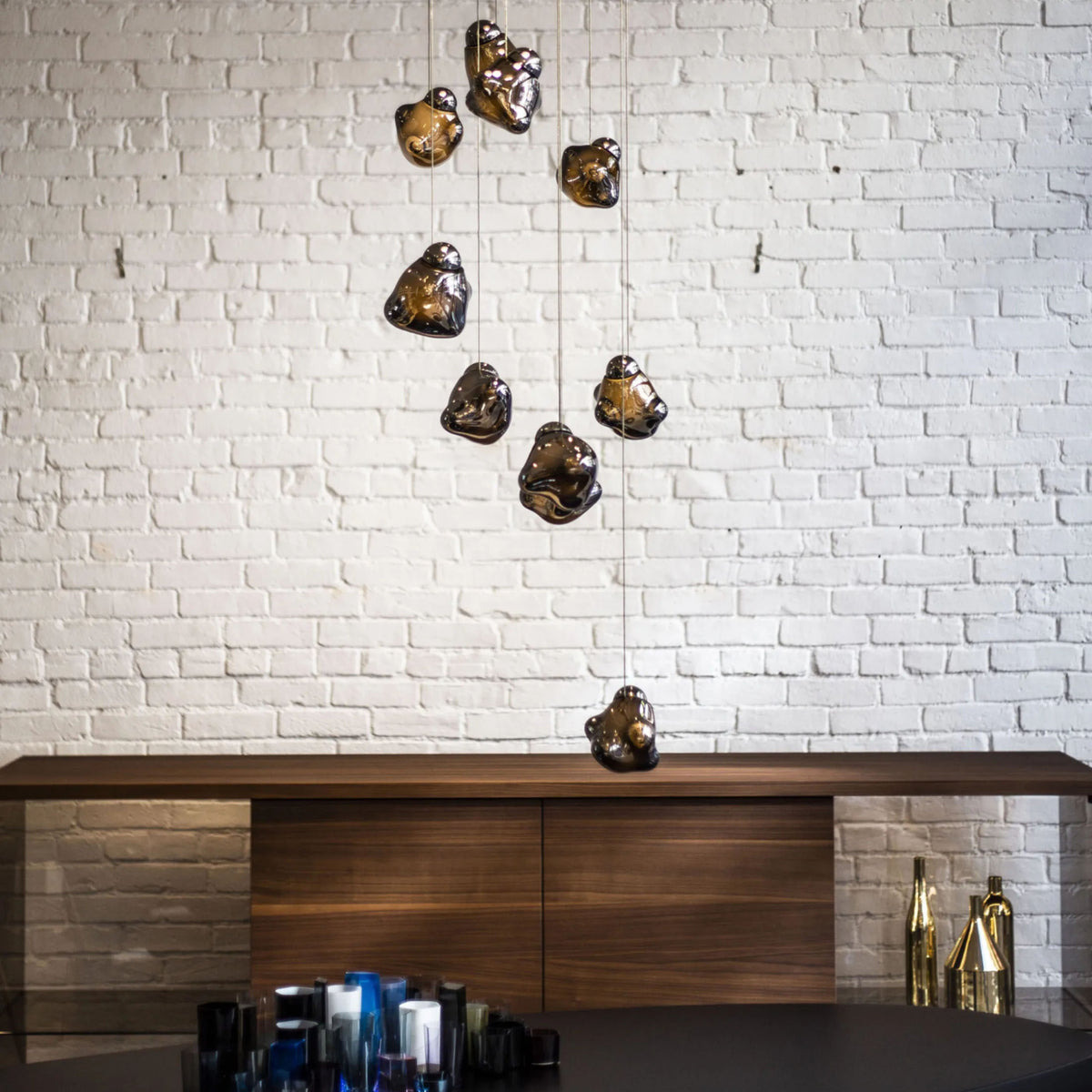 Bocci 57.5 Random by Omer Arbel. Bronze heart-shaped sculptures hang from thin wires against white brick.