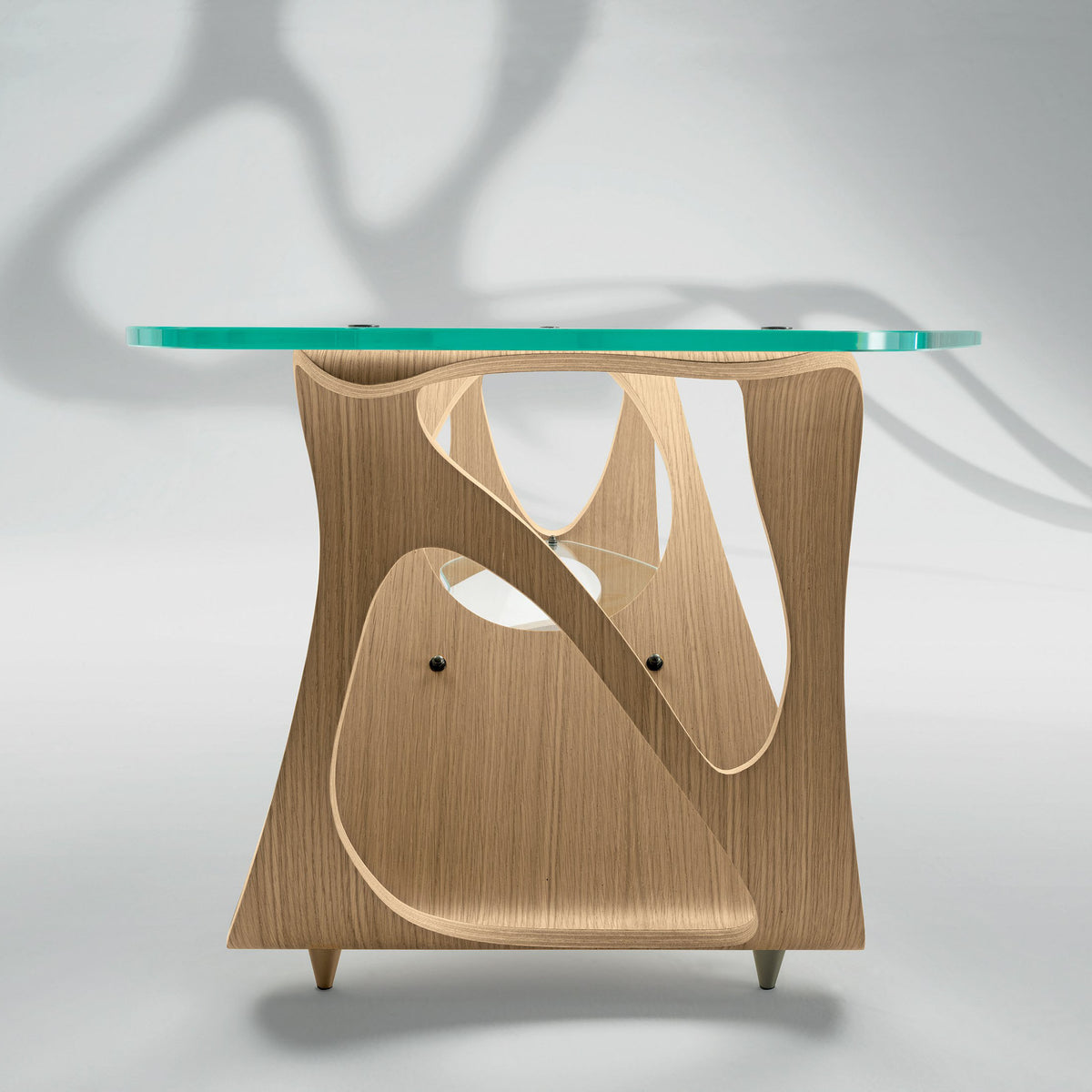Zanotta Arabesco CM by Carlo Mollino. A turquoise glass top rests on a sculptural wooden base with curved cutouts.