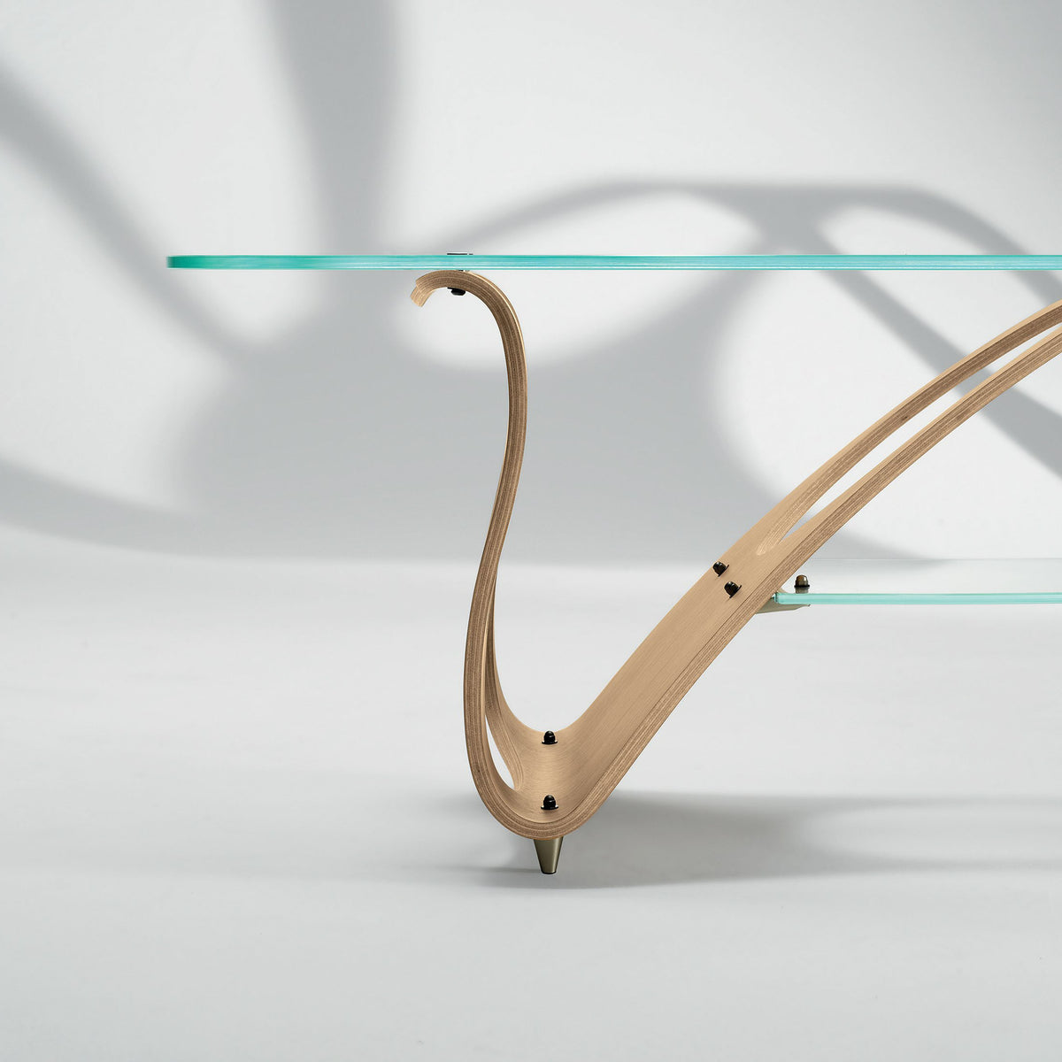 Zanotta Arabesco CM by Carlo Mollino. A turquoise glass tabletop rests on curved light wood legs with metal feet.
