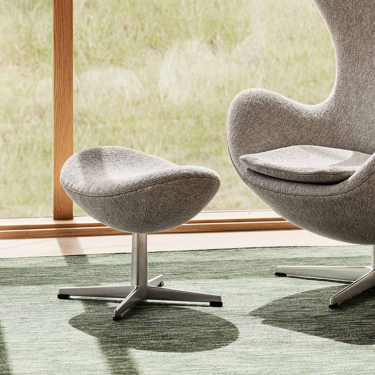 Fritz Hansen Egg™ Foot Stool - 3127 by Arne Jacobsen. Gray upholstered chairs with metal bases in a modern office setting.