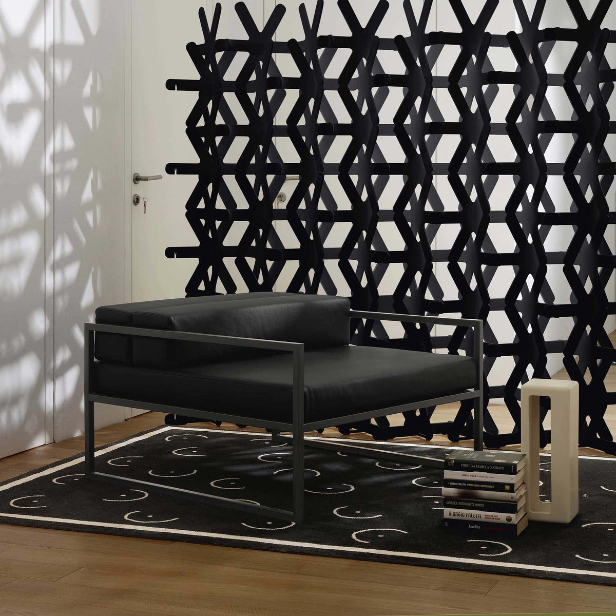 Cappellini Fronzoni '64 Armchair by AG Fronzoni 1964. Black leather chair with metal frame against geometric wall art.