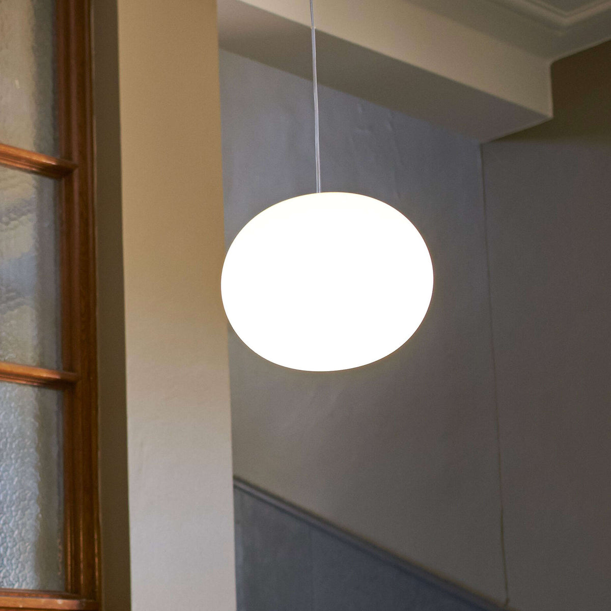 Flos Glo-Ball Suspension 1 by Jasper Morrison. A bright white spherical pendant light hangs in a modern hallway.