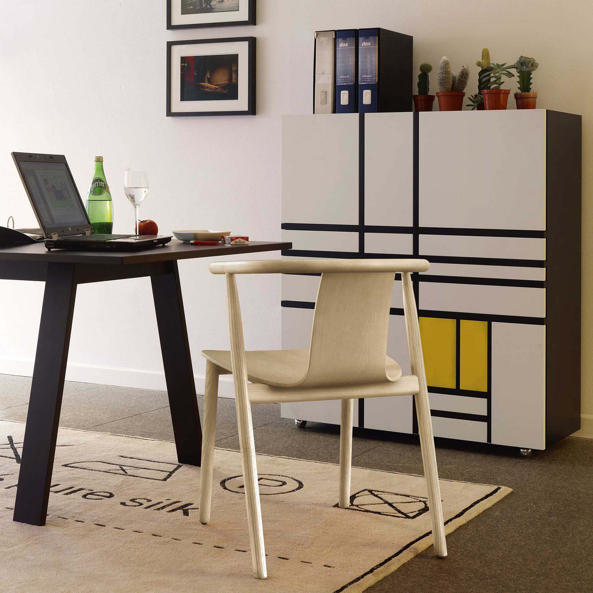 Cappellini Homage to Mondrian by Shiro Kuramata. A light wood chair sits in a modern office with black desk and storage unit.