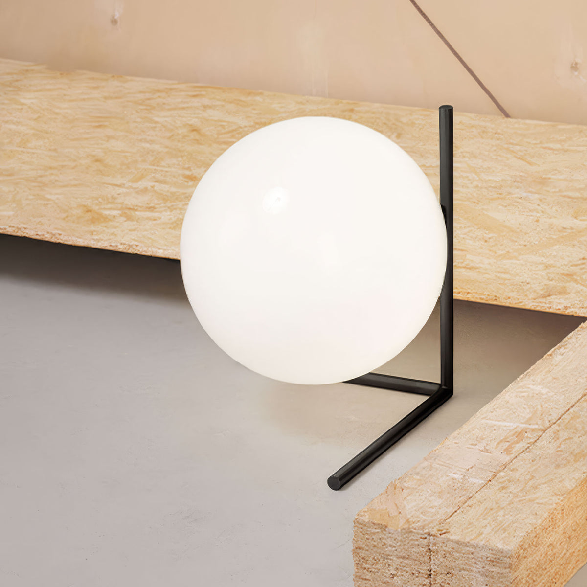 Flos IC Lights T2 by Michael Anastassiades. A glowing white sphere sits on a black metal stand between wooden beams.