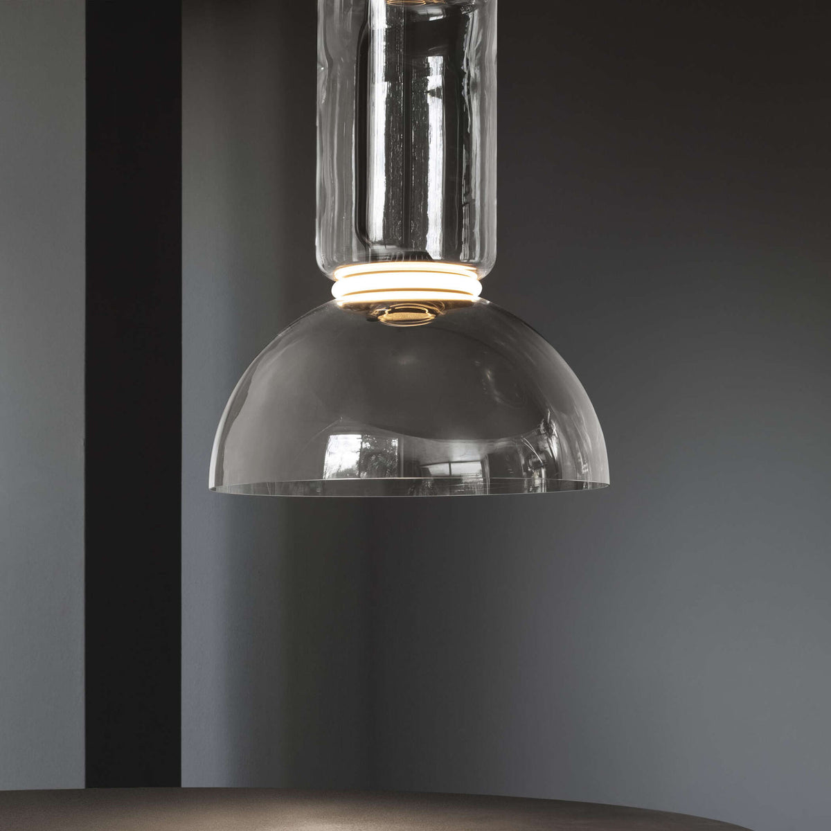 Flos Noctambule Suspension 1 Low Cylinder Bowl by Konstantin Grcic. A glass dome pendant with brass trim hangs elegantly.