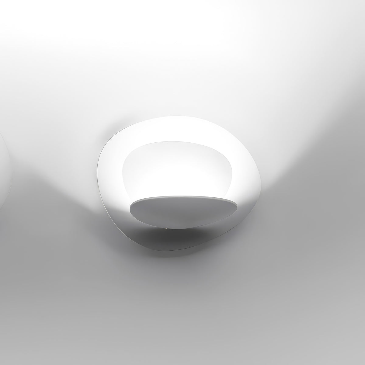 Artemide Pirce Parete by Giuseppe Maurizio Scutellà. A sleek white wall sconce with curved design casts soft light.