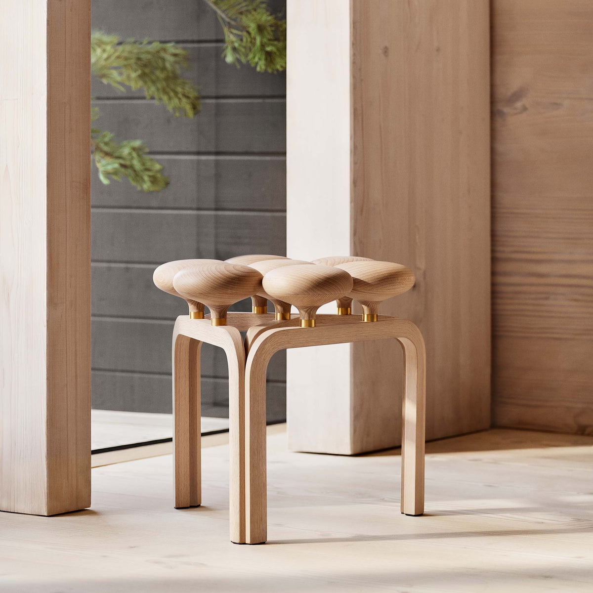 Fritz Hansen JU01™ Utzon Stool by Jørn Utzon. Light wood stool with curved seats and brass accents in a modern interior.