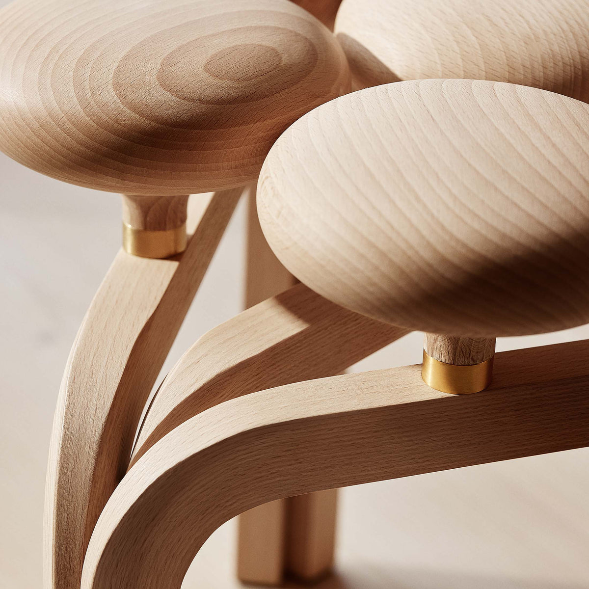 Fritz Hansen JU01™ Utzon Stool by Jørn Utzon. Natural wood furniture with curved forms and brass accents in warm tones.
