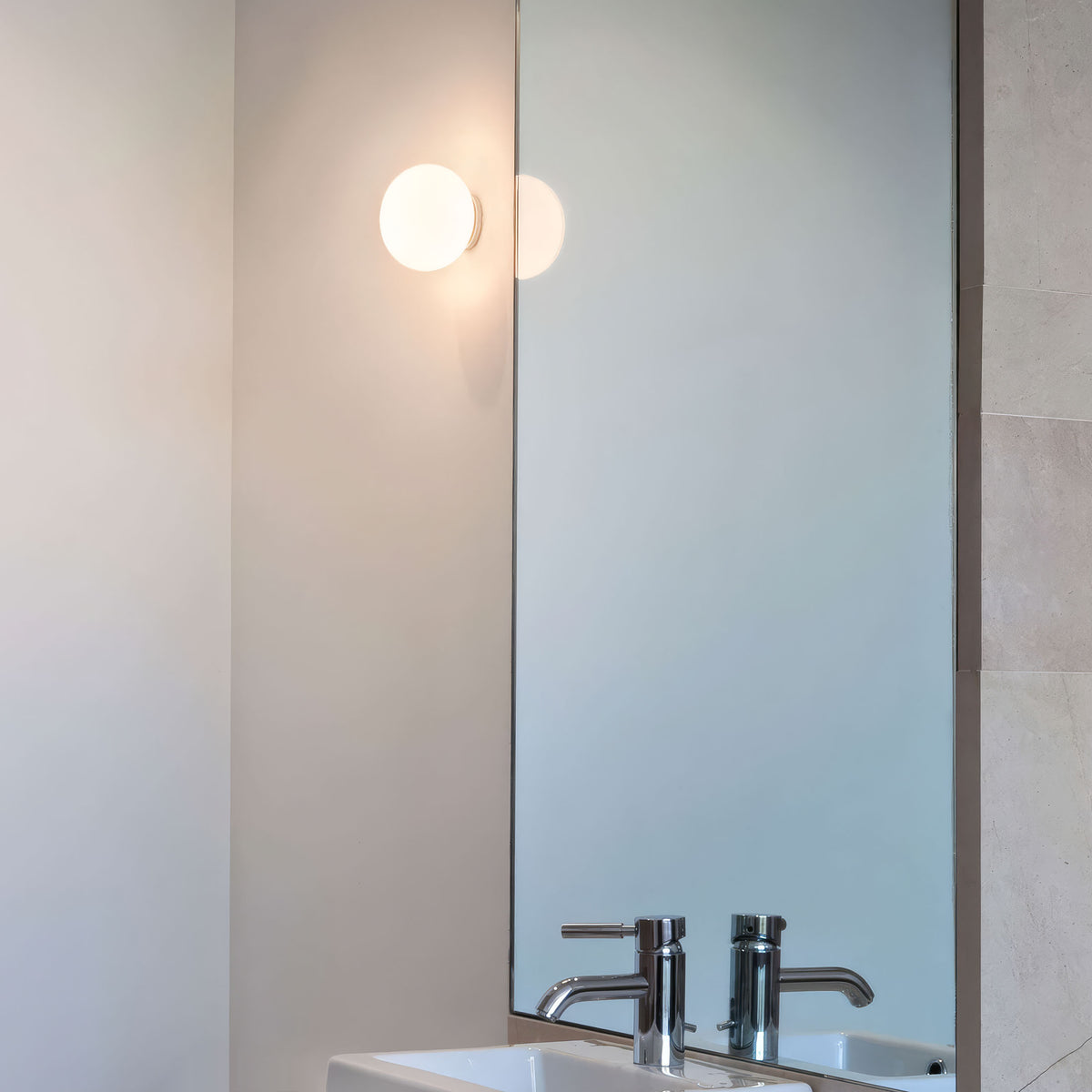 Flos Mini Glo-Ball Ceiling/Wall by Jasper Morrison. Modern bathroom mirror with circular lights above chrome faucets.