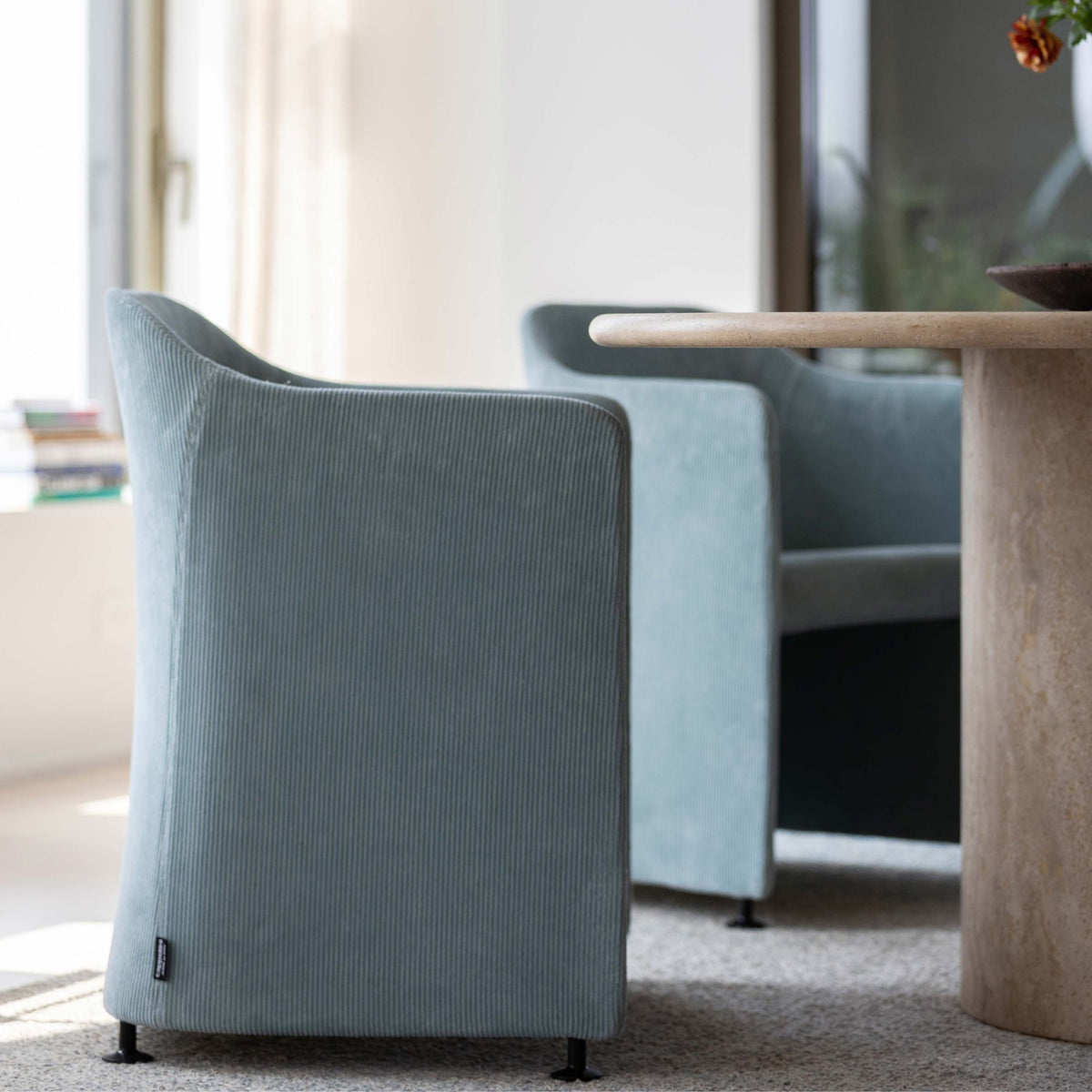 Cappellini San Siro by Jasper Morrison. Gray ribbed upholstered chairs sit beside a light wood table in bright sunlight.