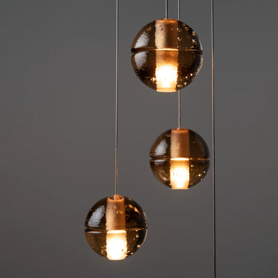 Bocci 14.20 Random by Omer Arbel. Three copper spheres with glowing centers hang from thin wires.