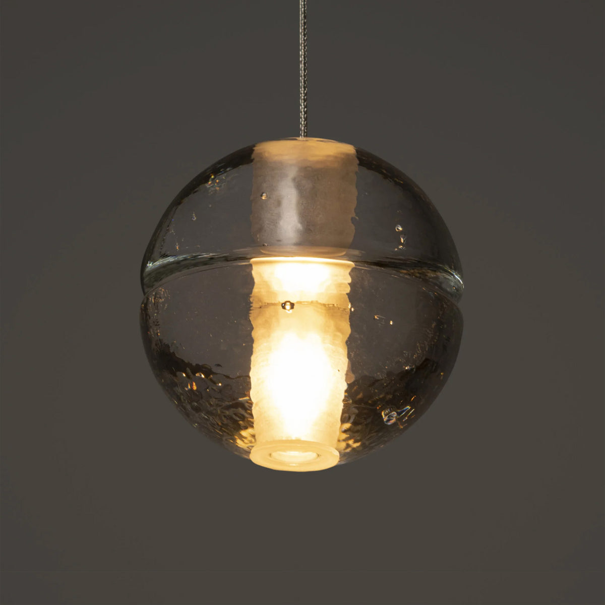 Bocci 14.5 Random by Omer Arbel. A glowing spherical pendant with smoky glass and warm brass accents hangs elegantly.