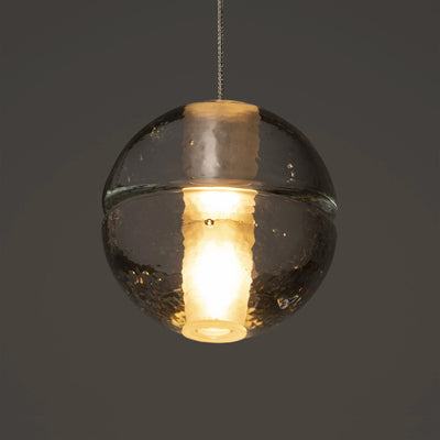 Bocci 14.5 Random by Omer Arbel. A glowing spherical pendant with smoky glass and warm brass accents hangs elegantly.