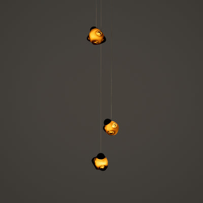 Bocci 57.3 Random by Omer Arbel. Three golden spherical lights hang vertically against a gray wall.