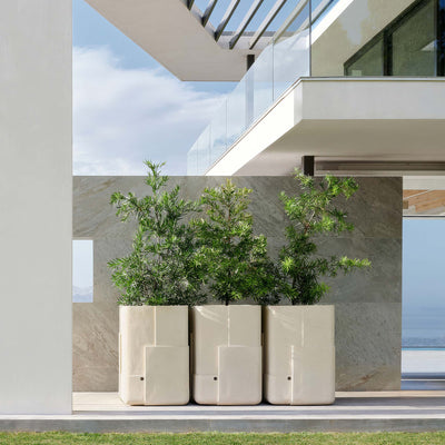 Indigenus Aarde by Sebastian Herkner. Three cream planters with green plants sit on a modern deck overlooking water.