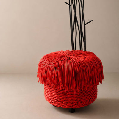 COVO Anemon Pouf by Rosanna Contadini. A vibrant red woven sphere with black wire stems emerges from a neutral gallery floor.