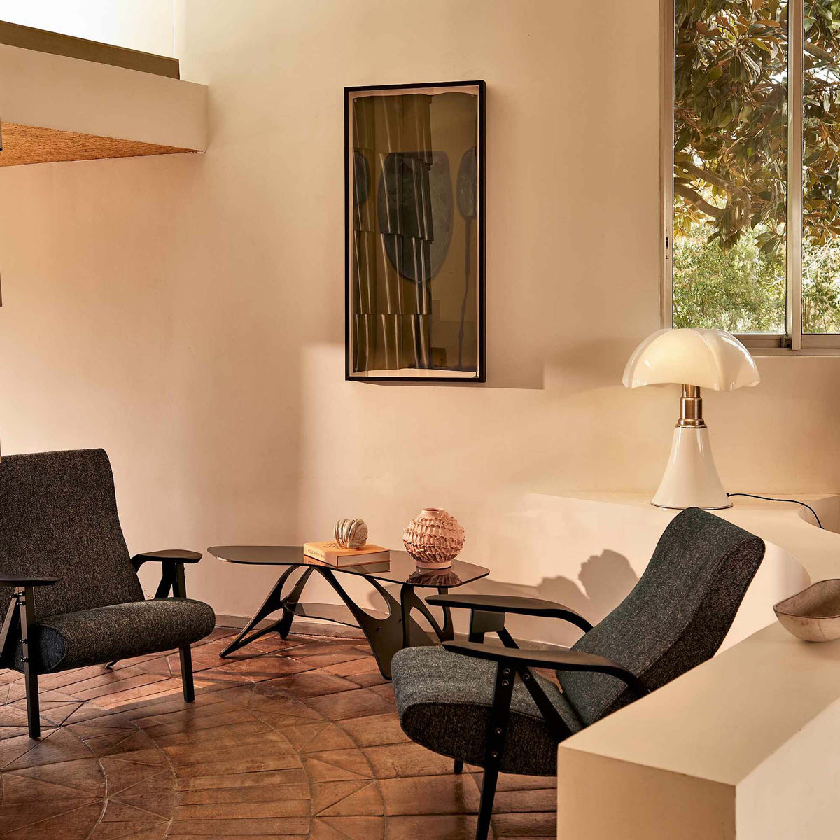 Zanotta Arabesco CM by Carlo Mollino. Two charcoal chairs face a sculptural black table in a warm, sunlit modernist space.
