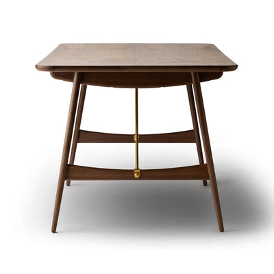 Carl Hansen & Søn BM1160 Hunting Table by Børge Mogensen. A wooden table with curved legs and brass accents.