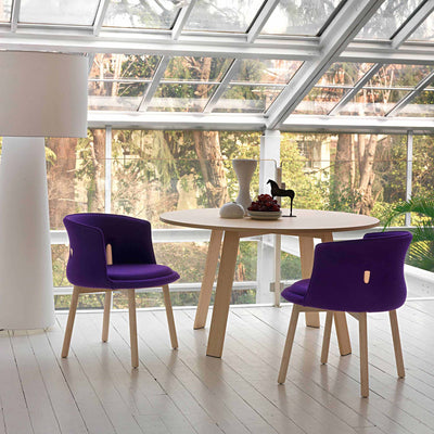 Cappellini Bac Table by Jasper Morrison. Purple chairs and a wooden table in a bright, modern room with large windows.