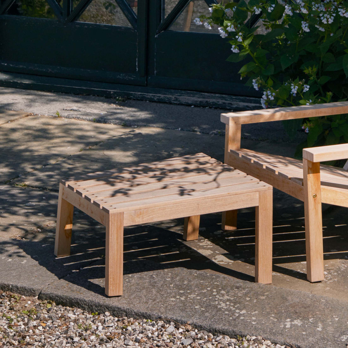 Fritz Hansen Between Lines Deck Stool by Stine Weigelt. Light wood furniture casts shadows in sunny garden setting.