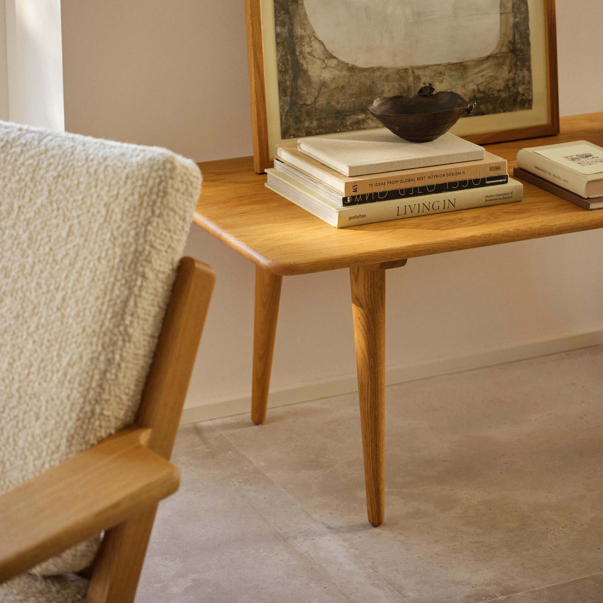 Carl Hansen & Søn CH011 Coffee Table by Hans J. Wegner. A wooden table holds stacked books and a dark bowl.