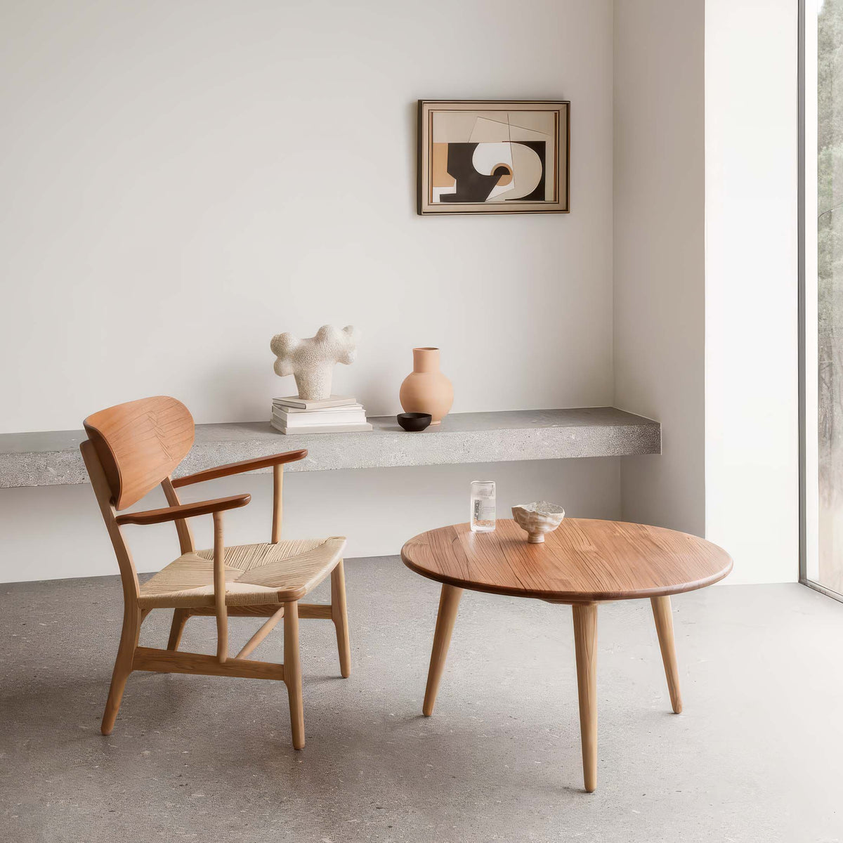 Carl Hansen & Søn CH22 Lounge Chair by Hans J. Wegner. Warm wood furniture sits in a minimalist room with neutral tones.