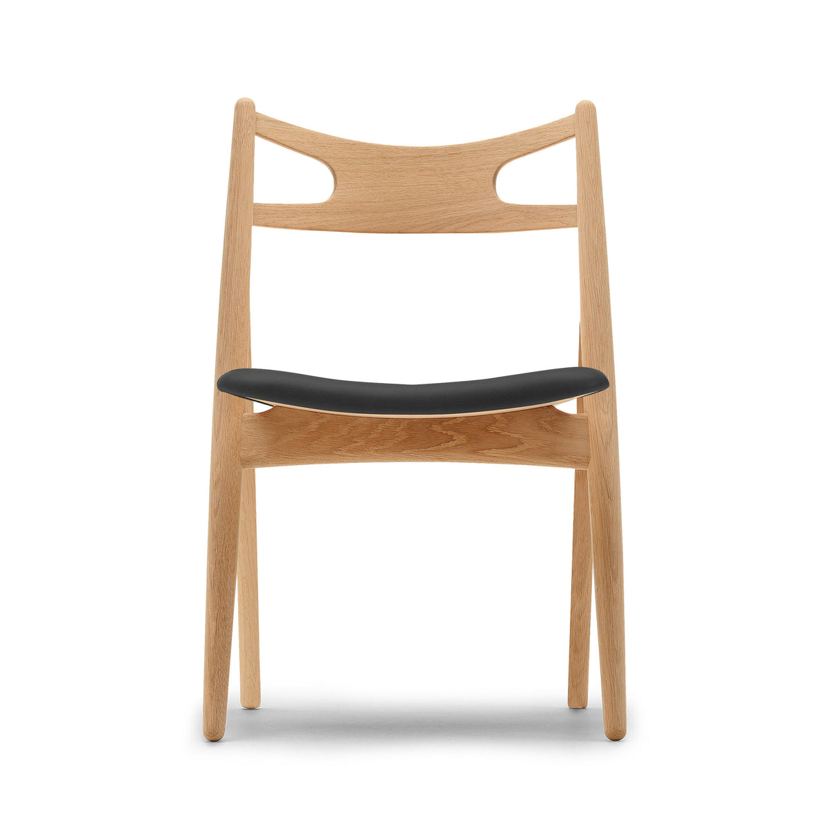Carl Hansen & Søn CH29P Sawbuck Chair by Hans J. Wegner. A natural wood chair with a black seat cushion.
