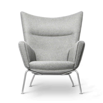 Carl Hansen & Søn CH445 Wing Chair by Hans J. Wegner. A grey upholstered wingback chair with metal legs.