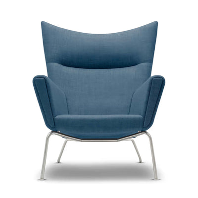 Carl Hansen & Søn CH445 Wing Chair by Hans J. Wegner. A blue upholstered chair with curved wings and metal legs.