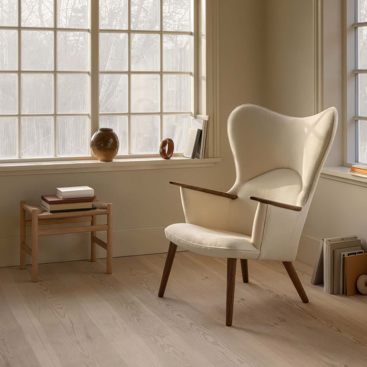 Carl Hansen & Søn CH78 Mama Bear Chair by Hans J. Wegner. A cream wingback chair with wooden arms sits in a sunlit room.
