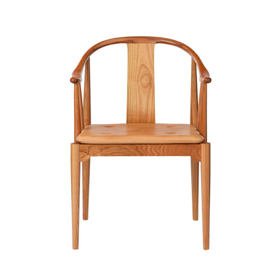 Fritz Hansen China Chair™ by Hans J. Wegner. A wooden chair with a curved back and tan cushioned seat.