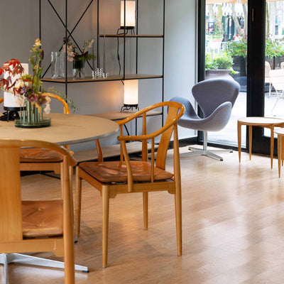 Fritz Hansen China Chair™ by Hans J. Wegner. Warm wooden chairs surround a round table in a bright, modern space.