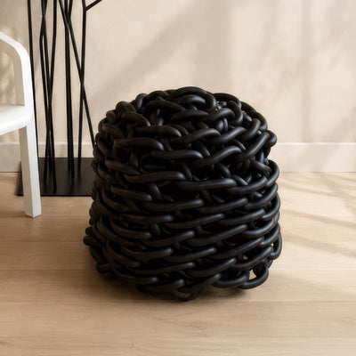 COVO Colosso pouf by Rosanna Contadini. A sculptural black object with interwoven tubular forms sits on wooden flooring.