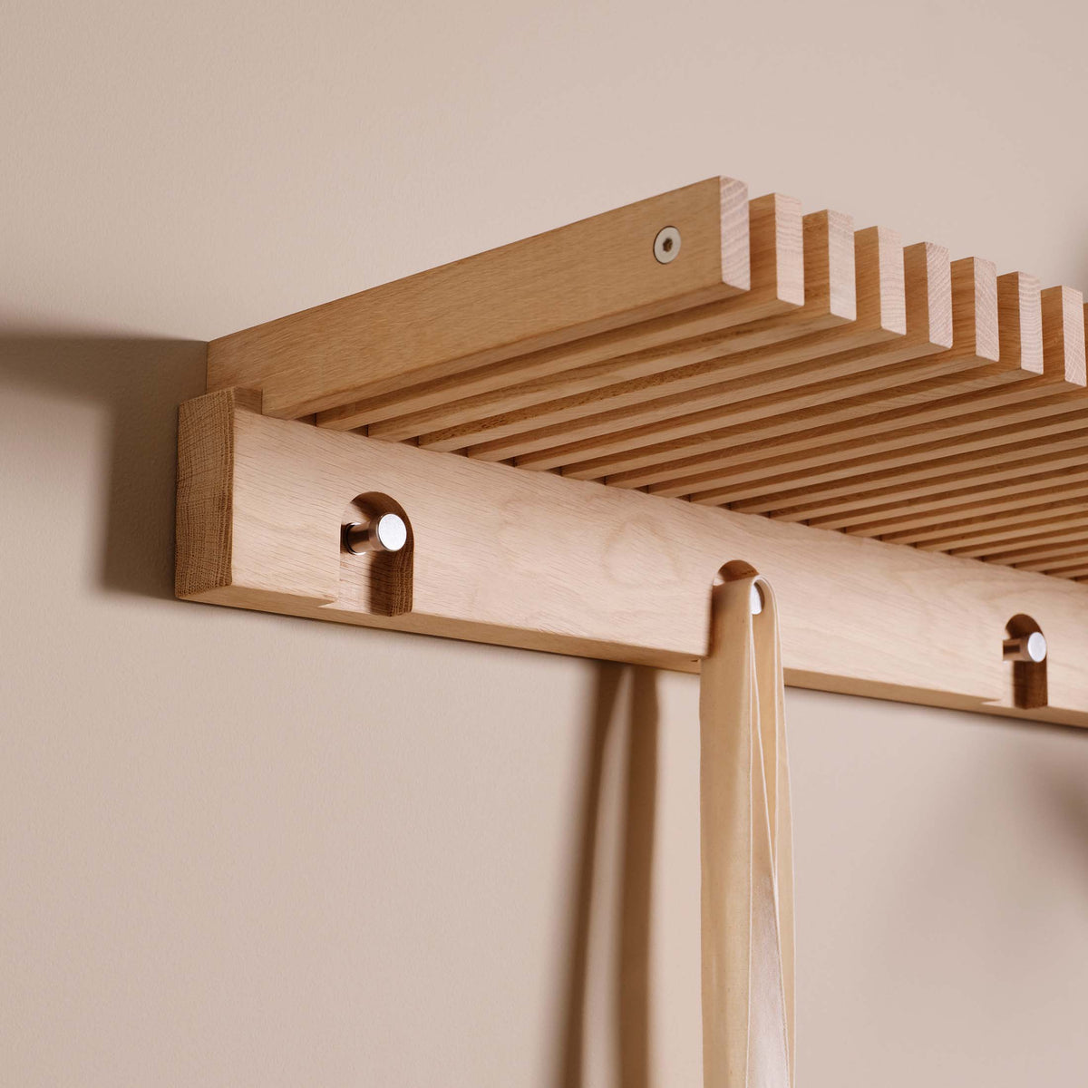 Fritz Hansen Cutter Wardrobe by Niels Hvass. Light wood shelf with pegs holds draped fabric against a pale wall.