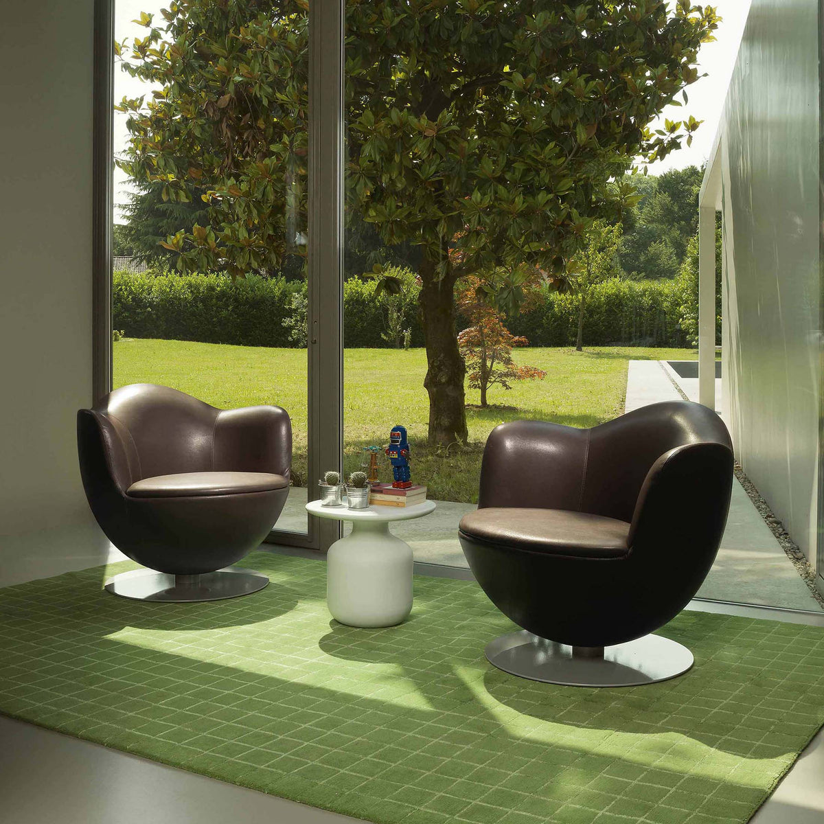 Cappellini Dalia by Marcel Wanders. Two black leather spherical chairs face each other across a white table in a sunlit room.