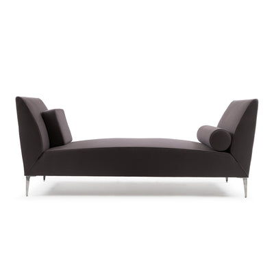 Cappellini Daybed by Jasper Morrison. A curved dark gray upholstered chaise with tapered metal legs and decorative pillows.