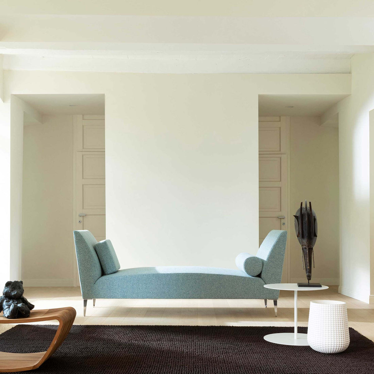 Cappellini Daybed by Jasper Morrison. A serene minimalist room features a light blue upholstered daybed with white pillows.