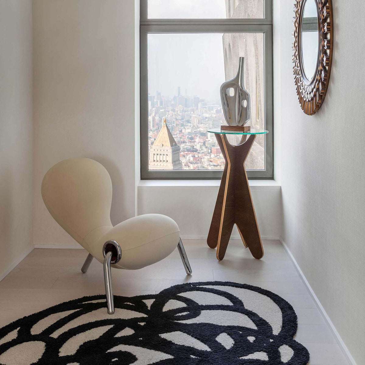 Cappellini Embryo Chair by Marc Newson. A cream chair sits beside a wooden table with a cityscape view.