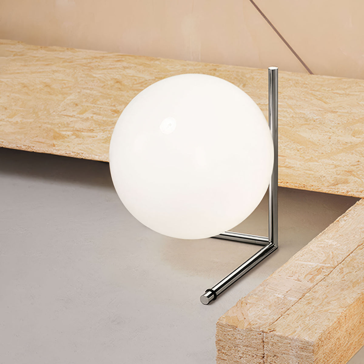 Flos IC Lights T2 by Michael Anastassiades. A white globe rests on a polished chrome stand against wooden beams.