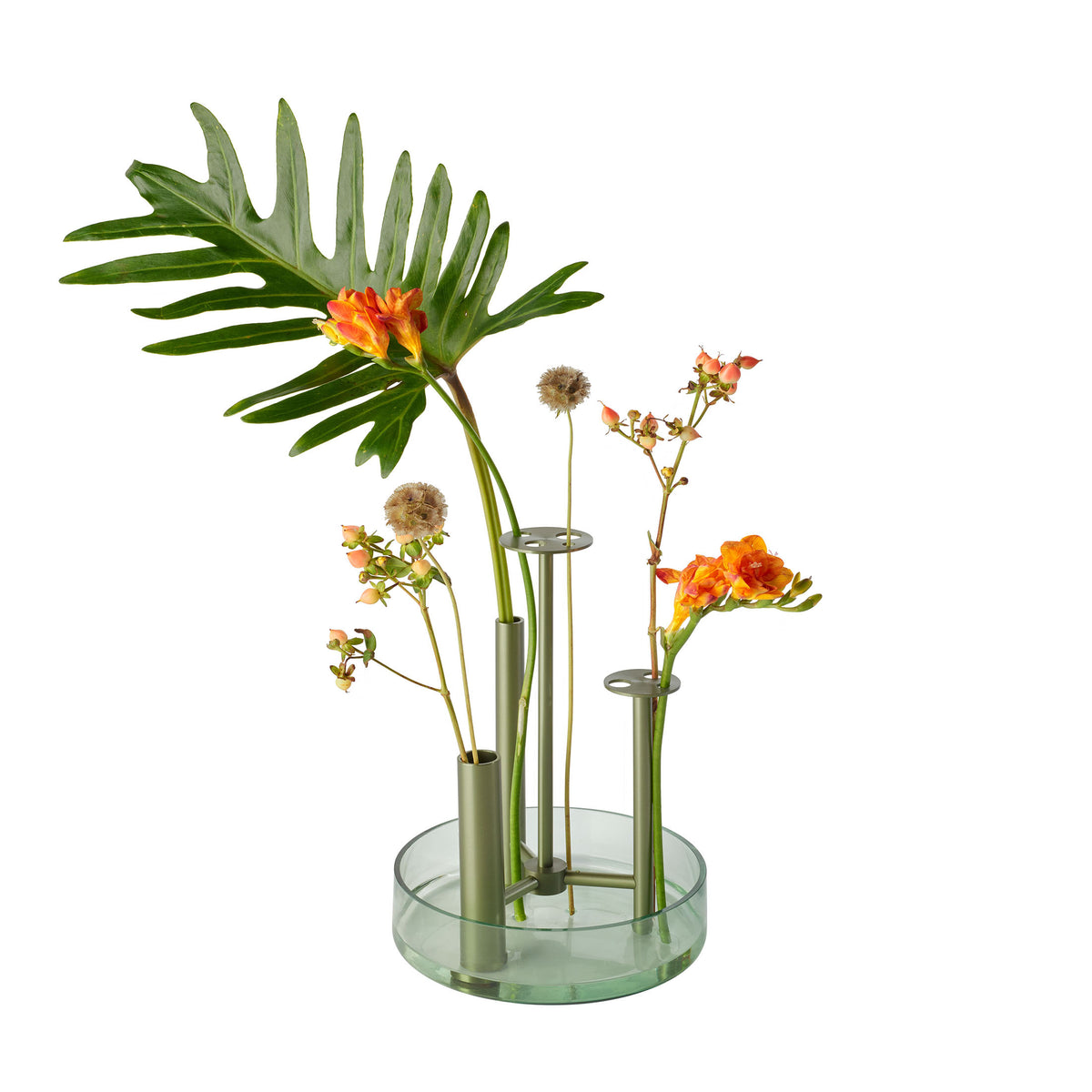 Fritz Hansen Ikeru™ Vase by Jaime Hayon. A glass vase with metal tubes holds orange and yellow flowers with green stems.
