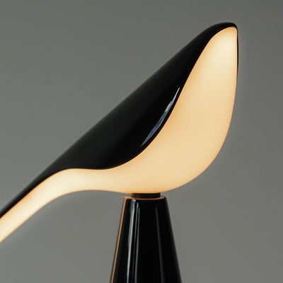 Established & Sons Tiki Table Lamp by Nao Tamura. A sleek black and cream chair curves elegantly against a gray background.