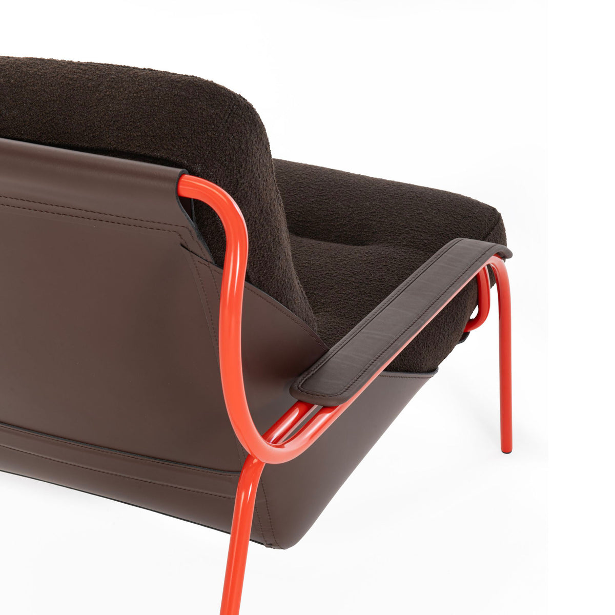 Zanotta Maggiolina by Marco Zanuso. A modern chair features dark grey upholstery with bright red metal frame and armrests.