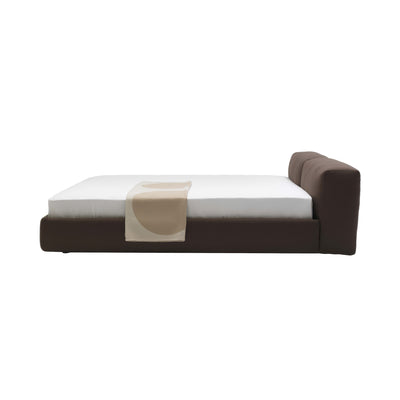 Cappellini Oblong Plus Bed by Jasper Morrison. A modern brown upholstered bed with white bedding and a beige throw.