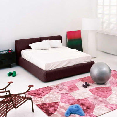 Cappellini Oblong Plus Bed by Jasper Morrison. A burgundy upholstered bed with white bedding sits in a minimalist bedroom.