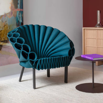 Cappellini Peacock by Dror. A striking teal sculptural chair with shell-like ribbed design sits in a modern room.