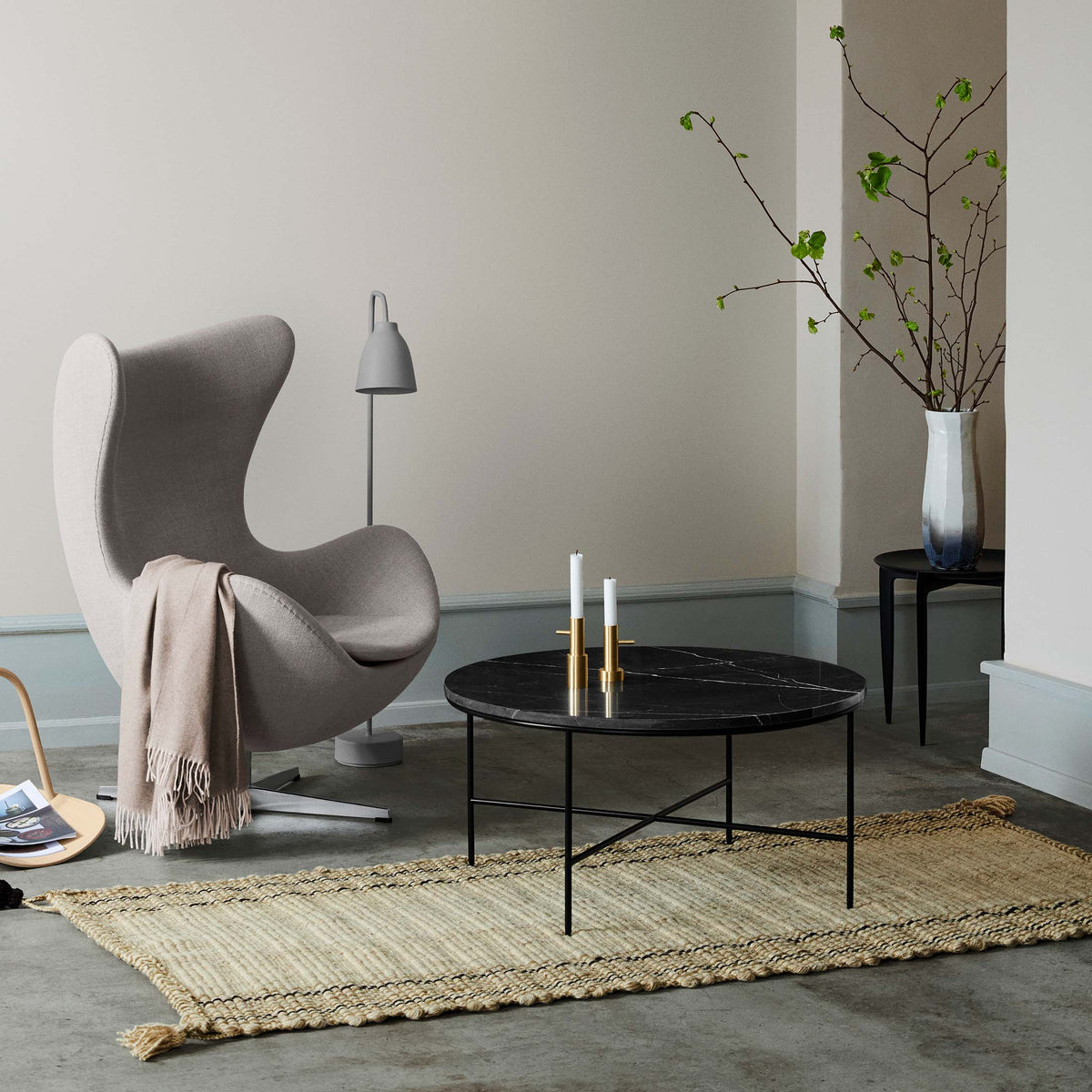 Fritz Hansen Planner™ MC300 Coffee Table by Paul McCobb. A grey chair sits beside a black marble table in a minimalist room.