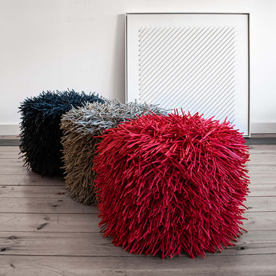 COVO Porcupine Pouf by Rosanna Contadini. Three spiky poufs in black, tan, and red sit on wooden flooring.