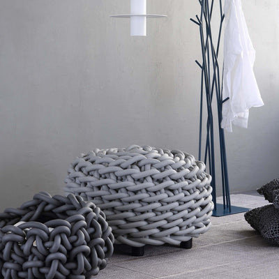 COVO Rebels 2 Pouf by Rosanna Contadini. A chunky braided rope basket sits on a textured gray rug in a minimalist white room.