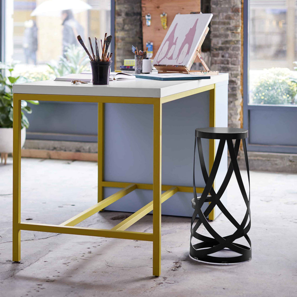 Cappellini Ribbon by Nendo. A modern desk with a white top and mustard yellow metal frame sits in a bright studio space.