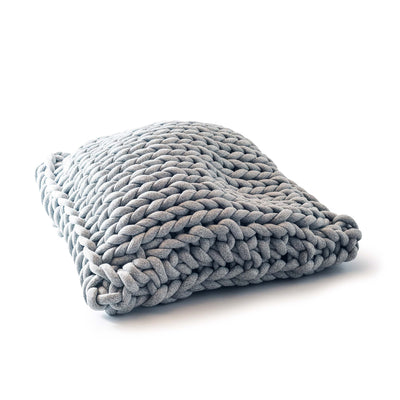 COVO Roxy Maxi Cushion by Rosanna Contadini. A chunky gray knitted blanket is folded on a white surface.